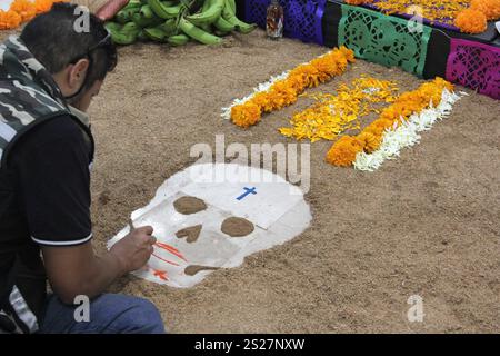 Der Mann gibt handgemachte Day of the Dead Opfergabe mit Schädeln, Cempasuchil-Blumen und Papel Picado, mexikanische Tradition Stockfoto