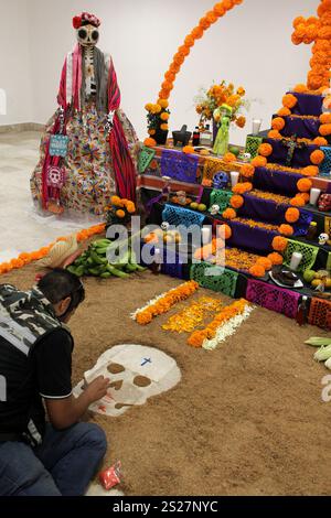 Der Mann gibt handgemachte Day of the Dead Opfergabe mit Schädeln, Cempasuchil-Blumen und Papel Picado, mexikanische Tradition Stockfoto