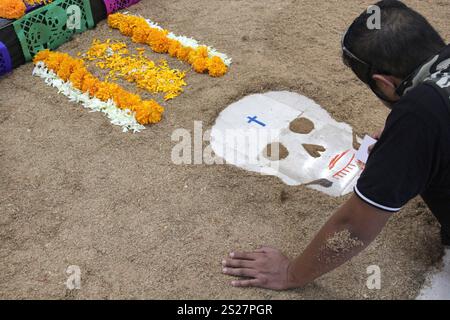 Der Mann gibt handgemachte Day of the Dead Opfergabe mit Schädeln, Cempasuchil-Blumen und Papel Picado, mexikanische Tradition Stockfoto
