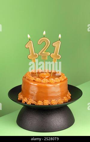 Nummer 121 Geburtstagskerze auf grünem Hintergrund - köstlicher Kuchen mit Dulce de leche Stockfoto