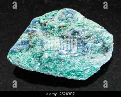 Makroaufnahmen von natürlichem Mineralgestein - rauer Fuchsite (Chrom Glimmer) Stein auf dunklem Granithintergrund aus Hizovaara, Republik Karelien in Stockfoto