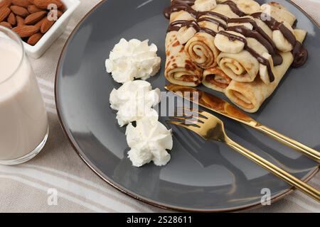 Köstliche Crepes mit Banane, Schokoladensoße und Schlagsahne serviert auf dem Tisch, Nahaufnahme Stockfoto