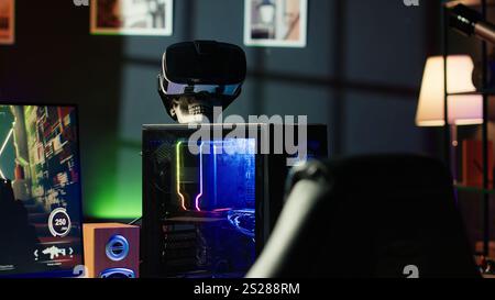 RGB-beleuchtete Teile am geöffneten Gaming-PC-Tower neben Tastatur, Stereo-Lautsprechern, Display und High-Tech-VR-Headset in leerem Apartment. Computer mit moderner Hardware, Monitor und Virtual-Reality-Brille Stockfoto