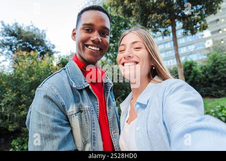 Fröhliche multirassische Freunde, die zusammen ein Selfie machen. Ein vielseitiges Paar, das Momente des Glücks und der Verbindung festnimmt, Freundschaft und Zweisamkeit feiert. Junges erwachsenes Paar, das in die Kamera schaut. Hochwertige Fotos Stockfoto