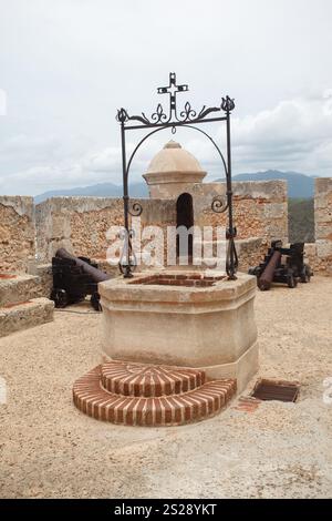 Zwei historische Bronzekanonen, ein Turm und ein Brunnen an den Festungsmauern von Castillo del Morro oder San Pedro de la Roca Festung aus dem 17. Jahrhundert Stockfoto