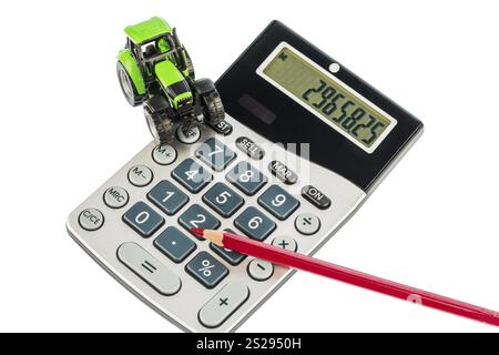 Ein Traktor und ein roter Stift auf einem Rechner. Kosten für Benzin, Verschleiß und Versicherung. Kosten und Subventionen in der Landwirtschaft Stockfoto
