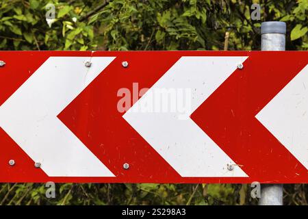 Ein rot-weißer Richtungspfeil auf einer Straßenmarkierung Stockfoto