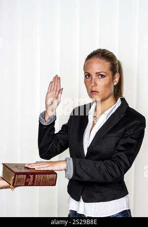 Eine Frau sagt als Zeugin in einem Gerichtsverfahren aus. Sie ist vereidigt und schwört auf die Bibel. Österreich Stockfoto