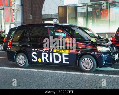TOKIO, JAPAN - 21. Dezember 2024: Taxis auf einer Hauptstraße in Tokios Ginza-Viertel mit einem Quersteg vor dem Eingang einer U-Bahn-Station Tokio. Stockfoto
