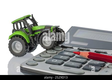 Ein Traktor und ein roter Stift auf einem Rechner. Kosten für Benzin, Verschleiß und Versicherung. Kosten und Subventionen in der Landwirtschaft Osterreich Stockfoto
