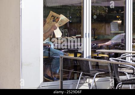 Ein Mann in einem Pub liest eine Zeitung. Zeitungsleser in einem Kaffeehaus Stockfoto