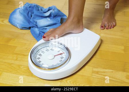 Die Füße einer Frau, die auf einer Badezimmerwaage steht Stockfoto