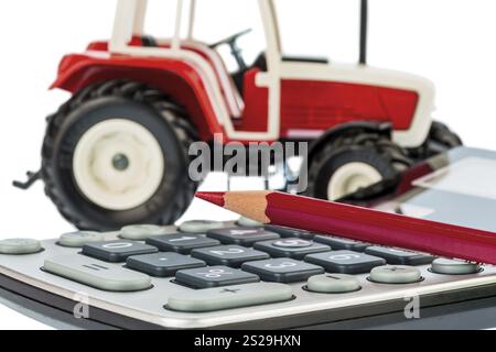 Ein Traktor und ein roter Stift auf einem Rechner. Kosten für Benzin, Verschleiß und Versicherung. Kosten und Subventionen in der Landwirtschaft Stockfoto