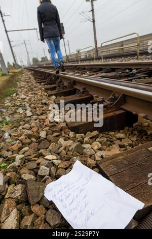 Eine junge Frau hinterlässt einen Abschiedsbrief und läuft auf einem Eisenbahngleis mit der Absicht, Selbstmord zu begehen. Brief auf Deutsch Stockfoto