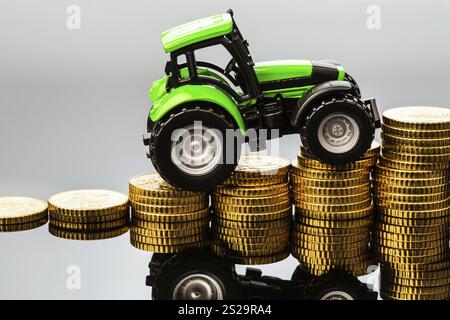 Die Landwirte in der Landwirtschaft müssen mit steigenden Kosten rechnen. Höhere Preise für Futtermittel, Düngemittel und Pflanzen. Traktor mit Münzen Österreich Stockfoto