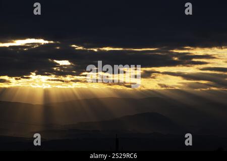 Sonnenstrahlen brechen durch die Wolken über einer Berglandschaft Österreichs Stockfoto