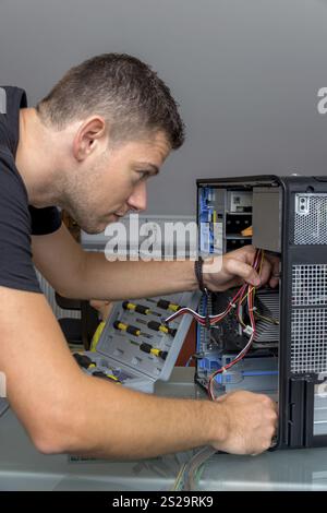 Ein Mann repariert einen Computer in einem Büro in Österreich Stockfoto