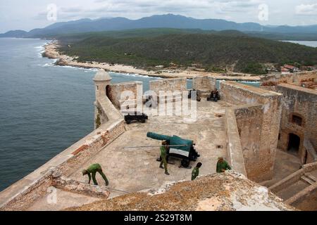 Vier Soldaten, historische Bronzekanonen und ein Turm an den Festungsmauern des Castillo del Morro oder der Festung San Pedro de la Roca aus dem 17. Jahrhundert Stockfoto