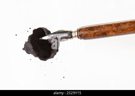 Blick von oben auf die braunen nib Stift über schwarze Tinte Fleck auf weissem Papier Stockfoto