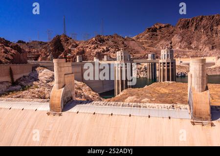 In der Ferne ist ein großer Damm mit einem blauen Himmel im Hintergrund zu sehen. Der Damm ist von einer felsigen Landschaft umgeben Stockfoto