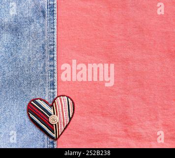 Hellblauer und korallenfarbener Denim-Hintergrund mit Filzherz im Patchwork-Stil. Denim-Jeans-Textur mit herzförmigem Textil-Patch. Valentinstag Stockfoto