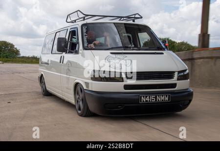 Knallte VW T4 Wohnmobil und modifizierter klassischer VW Käfer Stockfoto