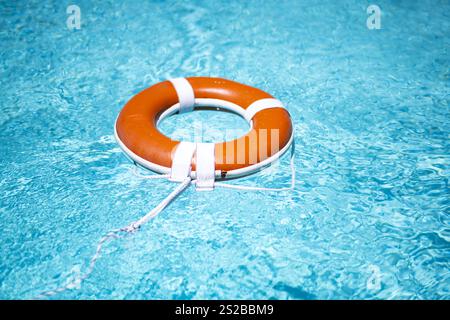 Kein Schwimmen. Ertrinkungskonzept. Rettungsring im Wasser. Sicherheitswasserausrüstung. Rettungsring auf dem Meer oder im Pool. Orangefarbener aufblasbarer Ring, der in Blau schwimmt Stockfoto