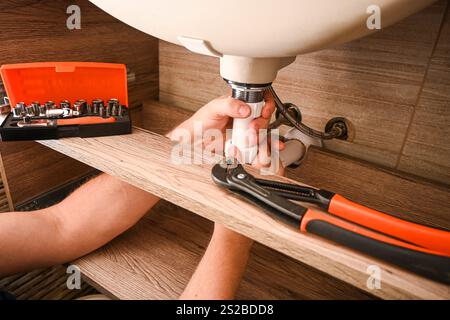 Professionelle Klempner arbeiten unter Waschbecken, befestigen Rohre und installieren neue Sanitäranlagen in modernen Badezimmern. Stockfoto