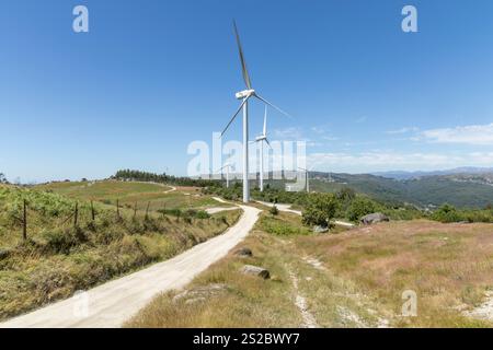 Große moderne Windmühlen in den Bergen mit einsamen Straßen und blauem Himmel in der Region Fafe in Portugal Stockfoto