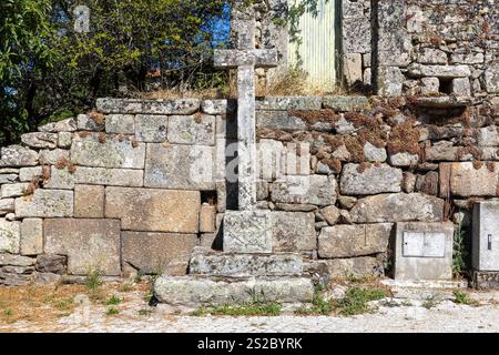 Religiöses Granit christentum Kreuz in einer Granitmauer mit Moos in einer Straße von Quintela Portugal Stockfoto