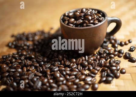 Schwarze Kaffeebohnen in einer Tasse auf einem Korb symbolisieren Natürlichkeit, Kaffee ist am Morgen sehr beliebt, um enthusiastischer zu sein Stockfoto