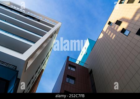 Modernes mehrstöckiges Wohngebäude mit lebhafter Fassade, großen Balkonen und malerischer Skyline unter klarem blauem Himmel Stockfoto