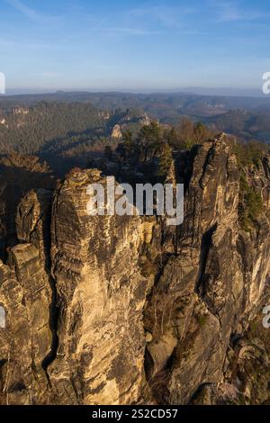Majestätische Klippen, die mit Kiefern bedeckt sind, erheben sich über dichten Wäldern. Vor dem Hintergrund des sanften Sonnenuntergangs. Blick von der Bastai-Brücke im sächsischen Schwezaria Na Stockfoto