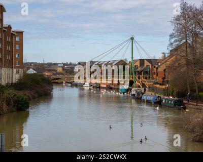 Blick auf den Fluss Nene bei Southbridge, Northampton, Großbritannien; mit modernen Wohnhäusern, verankerten Schmalbooten und der Wathen Wigg Bridge Stockfoto