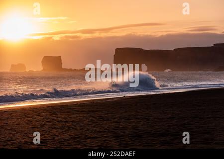 Wellen stürzen am schwarzen Sandstrand von Reynisfjara bei Sonnenuntergang, Süd-Zentral-Island, Island Stockfoto