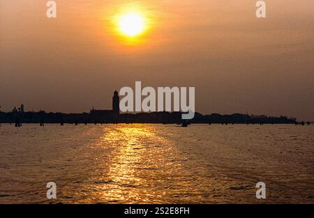 Farbenfroher Sonnenuntergang über dem Lido Pellestrina und der Lagune von Venedig, mit Reflektionen, Venedig, Italien. Stockfoto