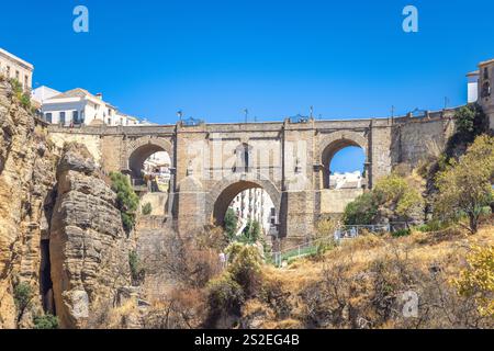 Die Brücke Puente Nuevo in der Schlucht El Tajo in Ronda in Spanien. Alte Steinbrücke, die eine tiefe Schlucht überspannt, mit Gebäuden auf beiden Seiten und zu sehen Stockfoto