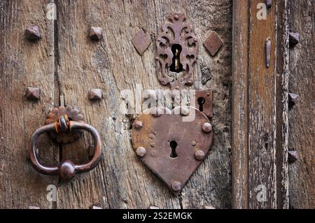 Alte verwitterte Tür mit herzförmigem Schloss, Schlüsselloch und Griff. Vintage-grungy-romantischer Hintergrund. Öffne dir das Herz, Homme ist, wo Liebe Konzepte ist. Stockfoto