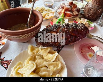 Eine Auswahl an festlichen Speisen, darunter dekoratives Brot, Knödel, süßes Gebäck und Suppe in Keramikgeschirr, die an kulturellen Reichtum in einem gemütlichen fa erinnern Stockfoto