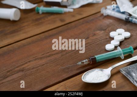 Eine Menge von Betäubungsmitteln und Geräte für die Zubereitung von Drogen liegen auf einem alten Holztisch. Drogendealer Material. Heroin und Methamphetamin im raw Stockfoto