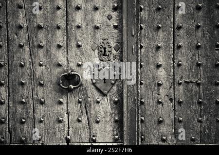 Alte verwitterte Tür mit herzförmigem Schloss, Schlüsselloch und Griff. Vintage-grungy-romantischer Hintergrund. Öffne dir das Herz. Schwarzweißes historisches Foto Stockfoto
