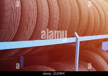 Rack mit verschiedenen Autoreifen im Automobilgeschäft. Viele schwarze Reifen. Hintergrund des Reifenstapels. Selektiver Fokus Stockfoto