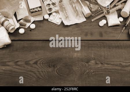 Eine Menge von Betäubungsmitteln und Geräte für die Zubereitung von Drogen liegen auf einem alten Holztisch. Drogendealer Material. Heroin und Methamphetamin im raw Stockfoto