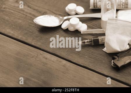 Eine Menge von Betäubungsmitteln und Geräte für die Zubereitung von Drogen liegen auf einem alten Holztisch. Drogendealer Material. Heroin und Methamphetamin im raw Stockfoto