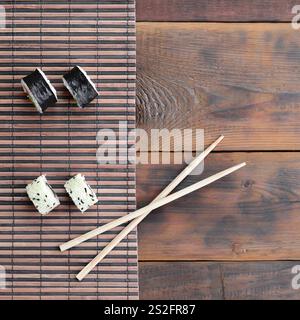 Sushi rollen und liegen auf einem hölzernen Eßstäbchen Bambus Stroh serwing Mat. Traditionelle asiatische Lebensmittel. Ansicht von oben. Stockfoto