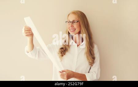 Schockiert und überrascht kaukasische reife Frau in Brille, die erstaunt über den hohen Preis auf dem langen Papierbeleg war Stockfoto