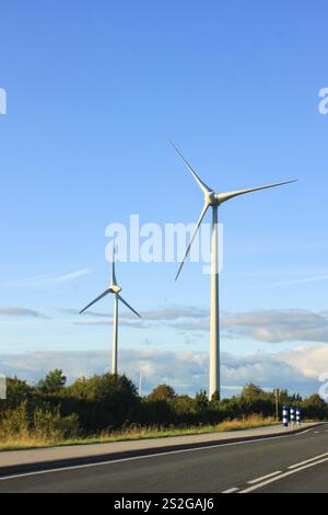 Zwei Windturbinen erzeugen Strom auf einem Hügel an der Straße Stockfoto