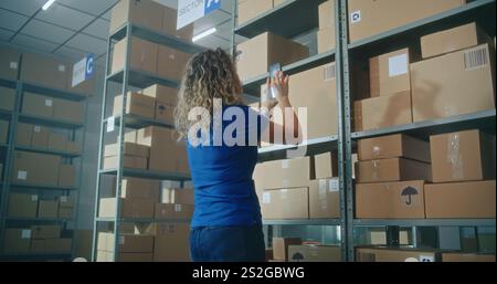 Eine Lagerbestandsmanagerin oder Logistikkoordinatorin scannt den Code auf dem Karton mit dem Smartphone und überprüft die Paketinformationen für die Lieferung an Kunden. Lagermitarbeiter, der im Vertriebszentrum arbeitet. Stockfoto