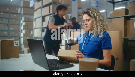 Die Lagerbestandsmanagerin scannt Pakete mit einem Barcode-Scanner, bereitet sich auf den Versand an Kunden vor, arbeitet mit einem Laptop. Lagermitarbeiter, die Kontrollkästchen für den Versand aktivieren. E-Commerce-Geschäft oder Postdienst. Stockfoto