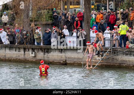 Thun, Schweiz - 8. Dezember 2024: Die Weihnachtsklauseln tauchen jährlich während des Weihnachtsmarktes in das kalte Wasser der Aare Stockfoto